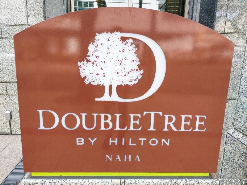 ダブルツリーbyヒルトン那覇のエントランスにある看板 茶色の背景に白地のロゴ