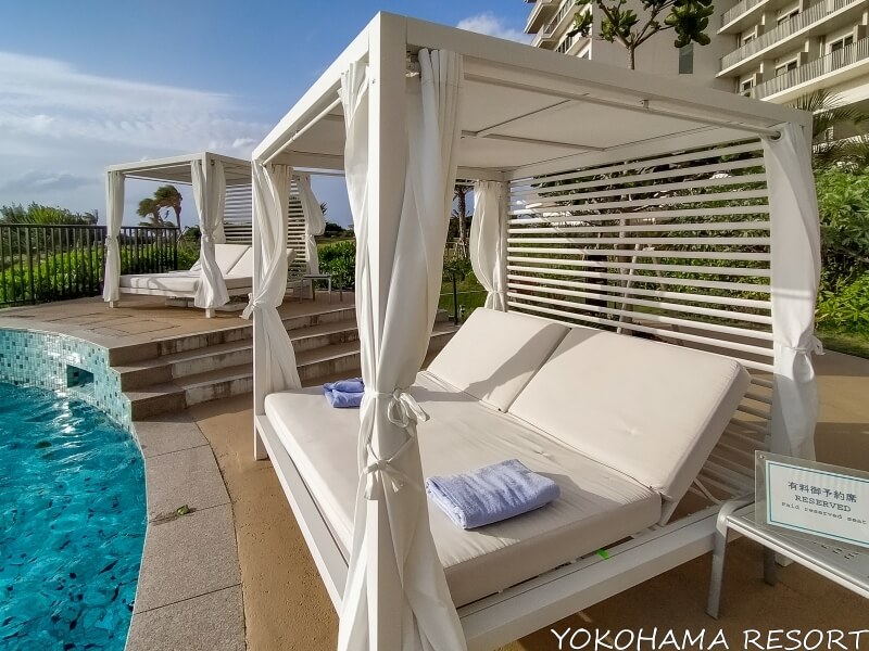 ヒルトン沖縄瀬底リゾートホテル 屋外プールサイドにある白いカバナ 白く大きなビーチベッドに水色のタオルが乗せてある
