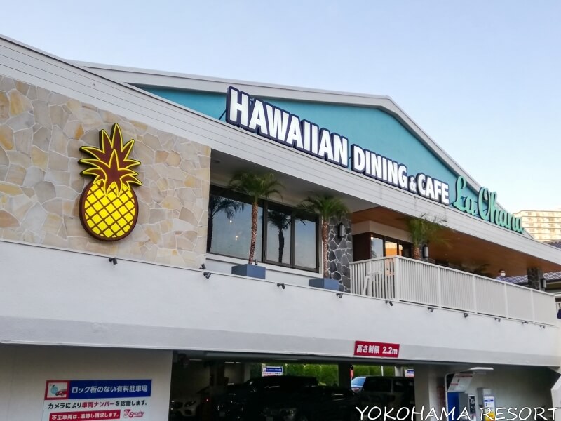 駐車場から見た店の外観 HAWAIIAN DINING & CAFE La Ohanaと書かれた店名のネオンと黄色いパイナップルマーク