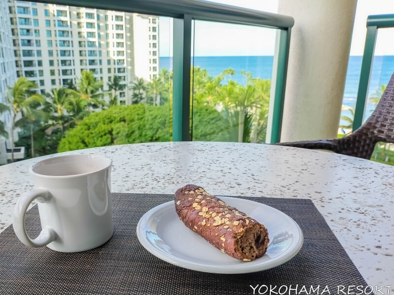 ラナイのテーブルの上にコーヒーとパン、海を見ながら