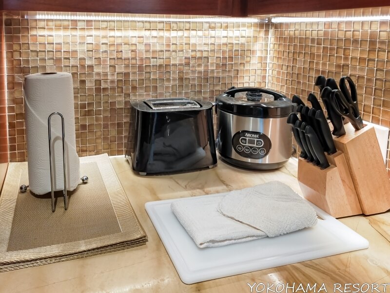 キッチン台にあるナイフ類、炊飯器、トースター、まな板、キッチンタオル、ランチョンマット