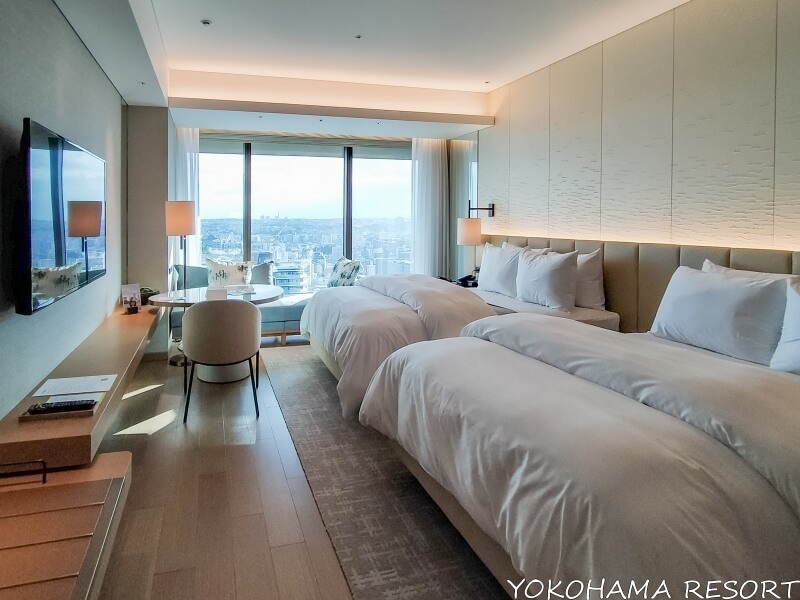 白い壁と白いシーツのベッド２台の明るい客室