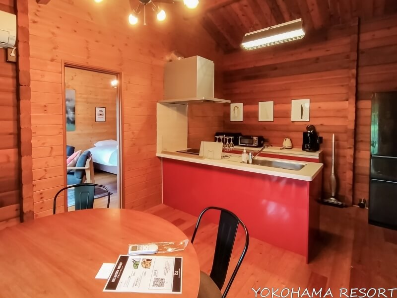 ログハウス風の室内に側面が赤いキッチン