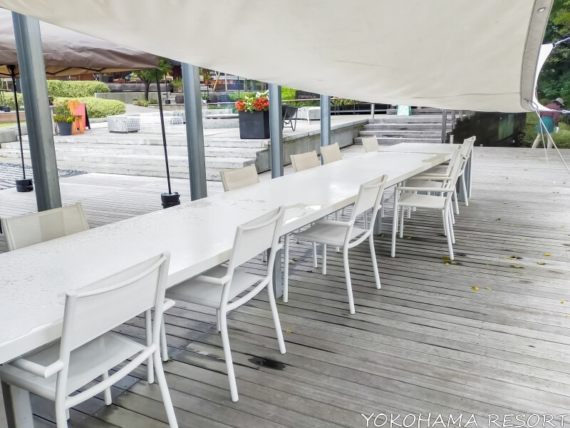白いタープの下に白い長テーブルと椅子が並ぶ