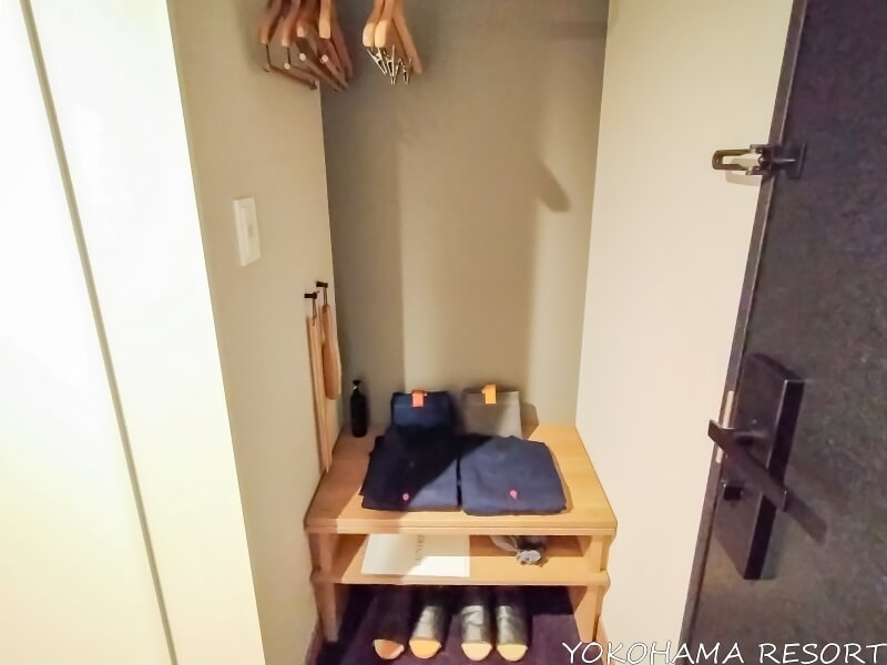 ハンガーの下の棚に紺のルームウェア、バッグ、サンダル