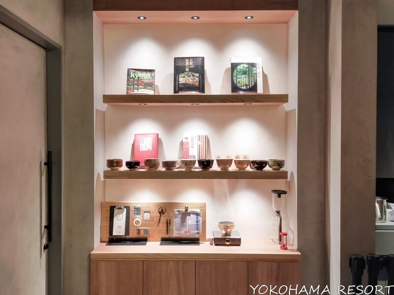 コンシェルジュデスクの後ろの棚に京都のガイドブックやお茶碗が並ぶ