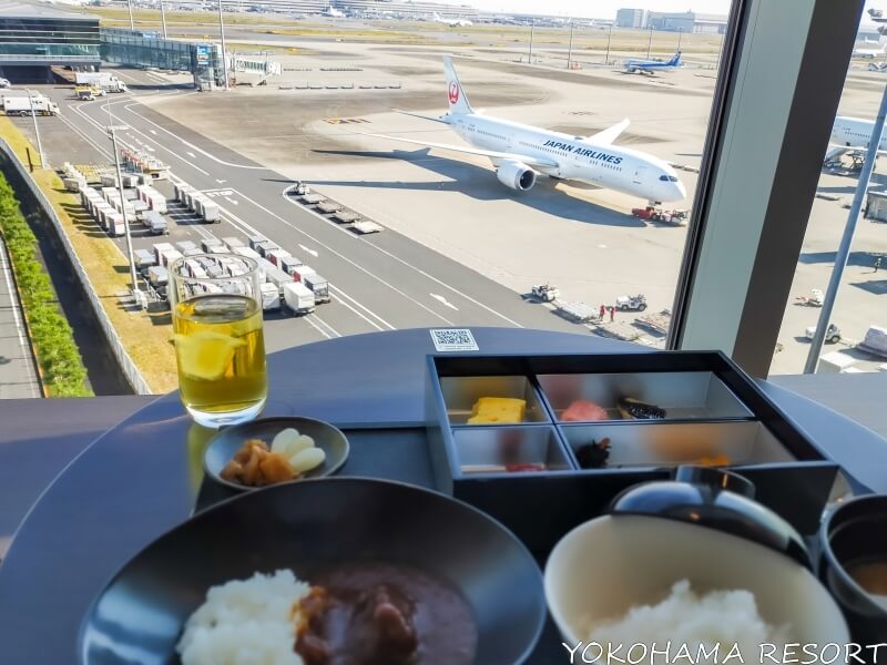 窓際の席で飛行機を見ながら食事