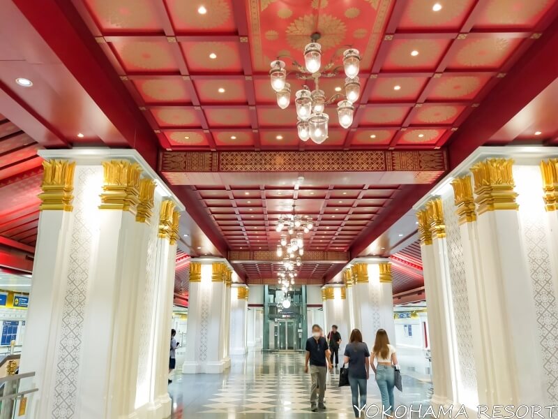 赤い天井と白い柱に金の装飾のある駅構内