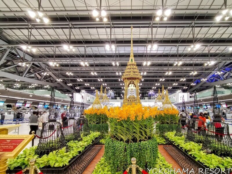 黄色い花と緑の植物に囲まれて金の仏塔が建っている