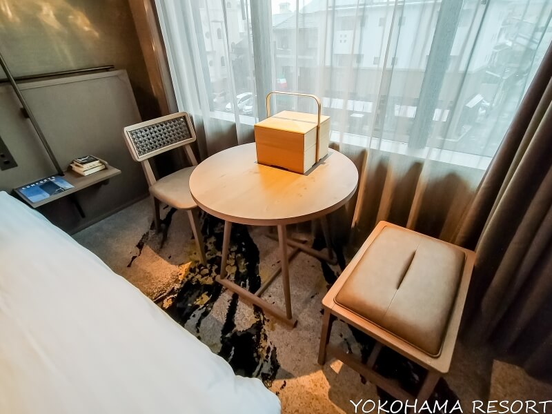 窓際の木製の丸テーブルとイス、テーブル上に正方形の茶箱